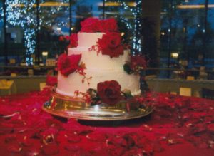 Fresh Flowers on a Beautiful Wedding Cake sitting on a bed of Red Rose Petals