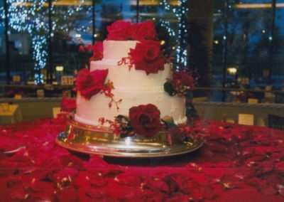 Fresh Flowers on a Beautiful Wedding Cake sitting on a bed of Red Rose Petals